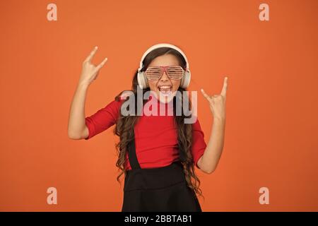 Accessoire de fête. Amuse-toi bien. Liste de lecture pour la fête. Concept de musique. Enfant porter des lunettes. Magasin de mode de lunettes. Piste froide. Fille avec lunettes arrière-plan orange. Événement et divertissement. Fille de fête. Banque D'Images