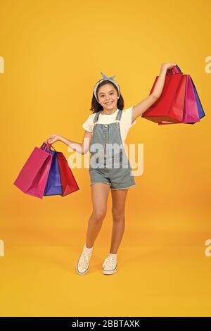 Traiter avec succès. Hurry up. Acheter plus rapidement. Happy girl with shopping bags. Petit enfant sourire avec des sacs en papier. Préparation et célébration des fêtes. Shopping sur le black friday. Shopping d'inspiration. Banque D'Images