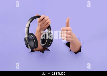 Les écouteurs Bluetooth se tiennent sur un fond bleu déchiré. Espace de copie. J'aime la musique. Comme la musique Banque D'Images