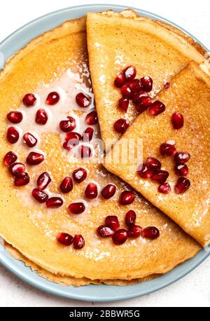 Les crêpes au grenade et au lait condensé se trouvent sur une assiette. Macro. Vue de dessus. Banque D'Images