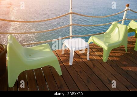 Table en plastique et deux chaises en plastique sur l'embarcadère pour prendre un café ou une boisson fraîche sur la plage. Banque D'Images