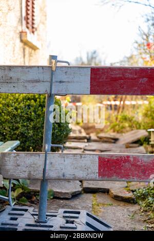 Barrière de construction dans la cour avant. Barricade pour le chantier de construction de l'arbre d'égout. Concentrez-vous sur le premier plan, pour le concept. Prise de vue verticale. Banque D'Images