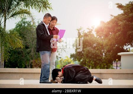 Cérémonie de remise des diplômes. Jeune femme diplômée donnant un certificat de diplôme à son parent à l'université. Banque D'Images