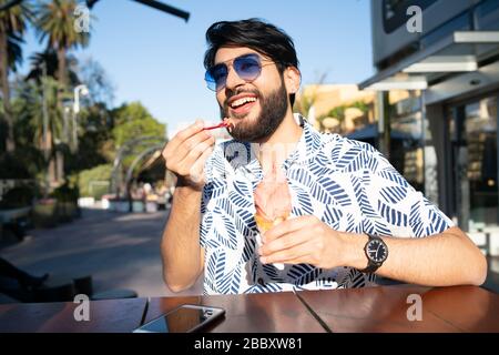 Portrait de jeune homme profitant du beau temps tout en mangeant une glace à l'extérieur. Banque D'Images