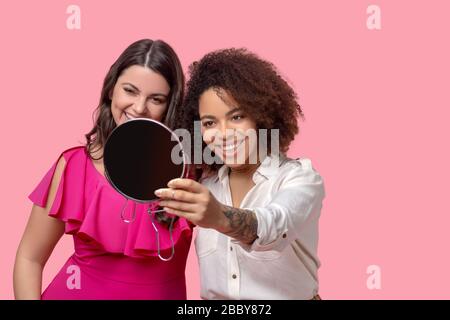 Deux copine regardant le miroir avec plaisir. Banque D'Images