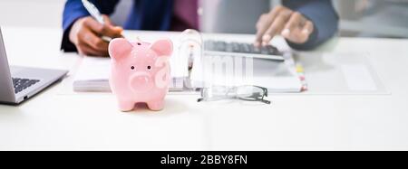 Bannière De La Piggybank Rose Devant La Personne D'Affaires Calculant Les Taxes Banque D'Images