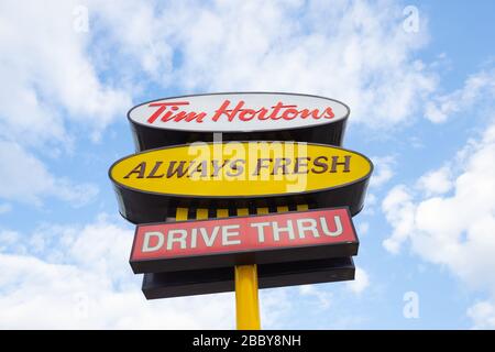 Panneau d'affichage montrant le logo et le texte du restaurant Tim Hortons fast food sur fond ciel Banque D'Images