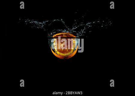 plongez la coupe orange sous l'eau avec un fond noir Banque D'Images