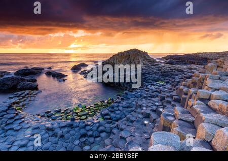 Un coucher de soleil épique sur la chaussée des Géants avec ses colonnes de basalte emblématiques. Comté d'Antrim, région d'Ulster, Irlande du Nord, Royaume-Uni. Banque D'Images
