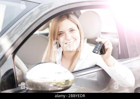 La jeune femme montre fièrement les clés de sa première voiture Banque D'Images