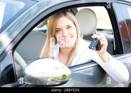 La jeune femme montre fièrement les clés de sa première voiture Banque D'Images