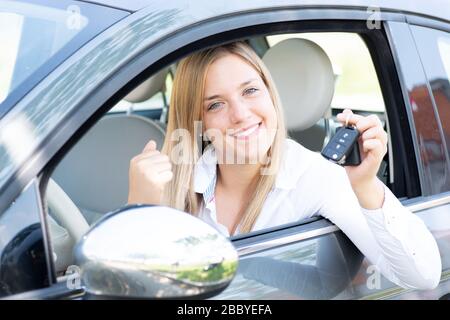 La jeune femme montre fièrement les clés de sa première voiture Banque D'Images