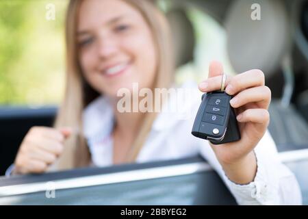 La jeune femme montre fièrement les clés de sa première voiture Banque D'Images