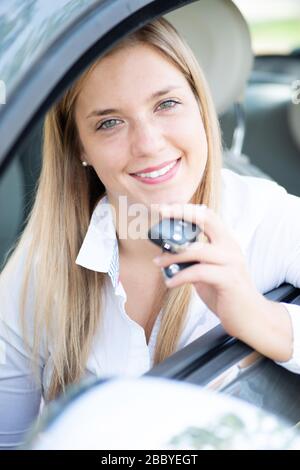 La jeune femme montre fièrement les clés de sa première voiture Banque D'Images