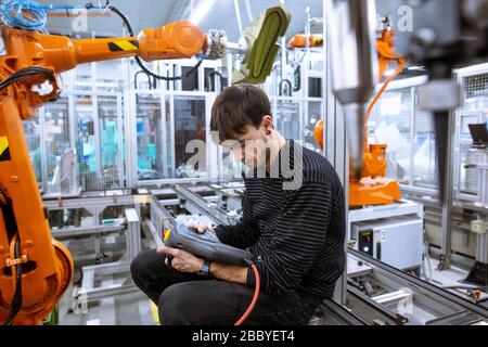 Programmateur programmant des bras de robot automatiques dans l'usine automobile intelligente, concept industriel Banque D'Images