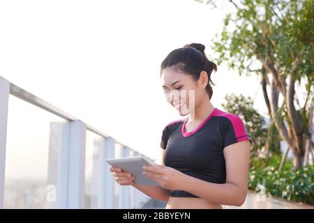 Une jeune femme gaie, l'entraîneur de forme physique, écrit sur son presse-papiers extérieur. Banque D'Images