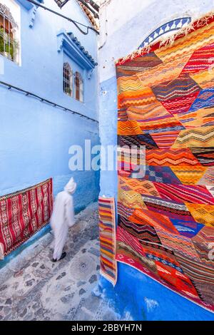 Chefchaouen, Maroc: Homme dans une djellaba blanche à pied dans la Médina Banque D'Images