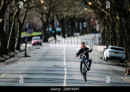 Cycliste fait une roue dans une rue calme de Glasgow, pendant le verrouillage du virus Corona. Banque D'Images