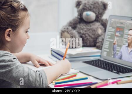 Jolie écolière étudiant les devoirs mathématiques pendant sa leçon en ligne à la maison, distance sociale pendant la quarantaine, auto-isolement, concept d'éducation en ligne Banque D'Images