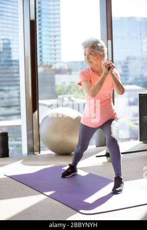 Femme chinoise senior s'exerçant à la salle de gym Banque D'Images