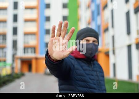 Arrêter l'infection. Homme en bonne santé montrant l'arrêt des gestes. Photo de l'homme porter un masque de protection contre les maladies infectieuses et la grippe. Concept de soins de santé Banque D'Images