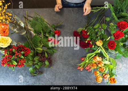 Une femme recueille un bouquet de fleurs printanières sur une table en pierre. Fleuriste en milieu de travail. Banque D'Images