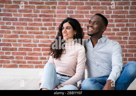 Portrait de jeunes couples multiethniques assis sur le sol dans leur nouvelle maison Banque D'Images