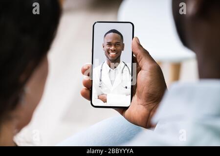 Couple ayant un chat vidéo avec Doctor sur le téléphone mobile à la maison Banque D'Images