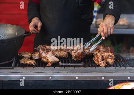 Cuisine de rue sur le gril. Viande sur brochettes, barbecue. En arrière-plan sont visibles les mains d'un homme qui fait cuire le kebab. À L'Extérieur. Photo horizontale. Banque D'Images