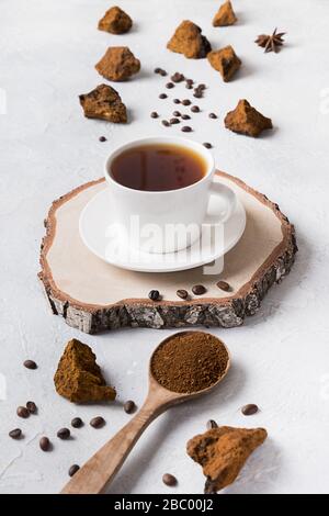 Composition verticale des champignons de chaga biologiques et du café sur fond clair. Boisson saine à la mode. Banque D'Images