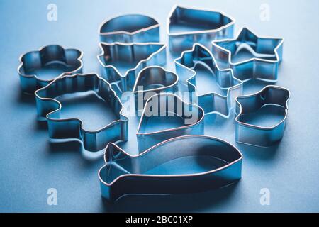 Moules métalliques pour cookies sur fond bleu. Moules à pâtisserie en forme de fête pour la fabrication de desserts décorés. Avec rétroéclairage à contraste lumineux. Banque D'Images