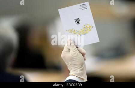 Magdeburg, Allemagne. 02 avril 2020. Un membre du Landtag portant des gants en caoutchouc tient une carte de vote pendant la session Landtag. Jeudi, le parlement de l'État a l'intention d'adopter le budget supplémentaire de 500 millions d'euros pour faire face à la crise de Corona en deuxième lecture. Crédit: Ronny Hartmann/dpa/Alay Live News Banque D'Images