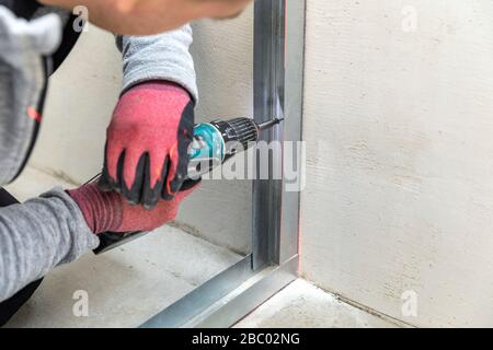 l'homme fixe le cadre profilé métallique au mur pour la cloison de la paroi de drainage Banque D'Images