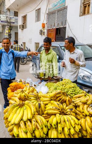 Homme local vendant des fruits d'un barrow au bord de la route: Scène de rue dans le quartier de Mahipalpur, une banlieue près de l'aéroport de Delhi à New Delhi, capitale de l'Inde Banque D'Images