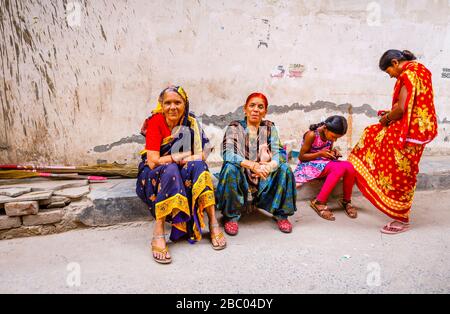 Scène de rue dans le district de Mahipalpur, une banlieue près de l'aéroport de Delhi à New Delhi: Des femmes assis sur le côté d'une rue et une mère et fille Banque D'Images