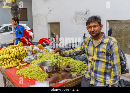 Homme local vendant des fruits d'un barrow au bord de la route: Scène de rue dans le quartier de Mahipalpur, une banlieue près de l'aéroport de Delhi à New Delhi, capitale de l'Inde Banque D'Images