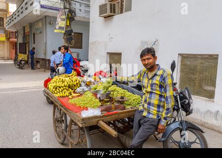 Homme local vendant des fruits d'un barrow au bord de la route: Scène de rue dans le quartier de Mahipalpur, une banlieue près de l'aéroport de Delhi à New Delhi, capitale de l'Inde Banque D'Images