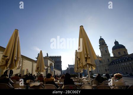 Les gens aiment le soleil se réchauffer devant le café Tambosi sur Odeonsplatz, le jour de janvier. [traduction automatique] Banque D'Images