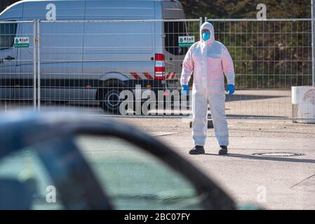 Un employé de la station de conduite pour prendre des écouvillons en cas de suspicion justifiée d'infection par le virus corona instruquera les voitures arrivant dimanche 22 mars 2020 à la Theresienwiese à Munich (Haute-Bavière). [traduction automatique] Banque D'Images