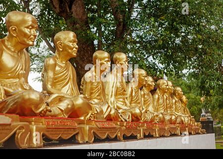 Une rangée de statues de moine doré dans le jardin du temple Wat Phra que Chae Haeng. Banque D'Images