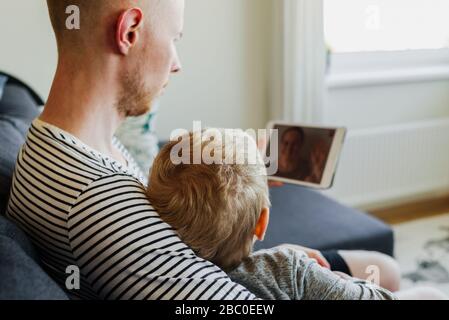 Père et fils ayant un appel vidéo à la mère à l'aide d'une tablette. La famille communique par Internet Banque D'Images