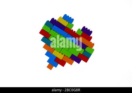 Une forme de coeur faite avec beaucoup de différents blocs de construction de couleur devant un fond blanc isolé Banque D'Images