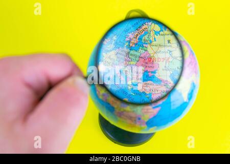 Gros plan d'une main tenant une loupe pour regarder le globe dans la bibliothèque sélective Focus Ukraine Banque D'Images