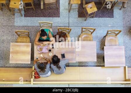 Vue sur trois amis féminins dans le café pendant la pause déjeuner. Tables en bois et style rétro. Concept d'amitié et de pause déjeuner. Banque D'Images