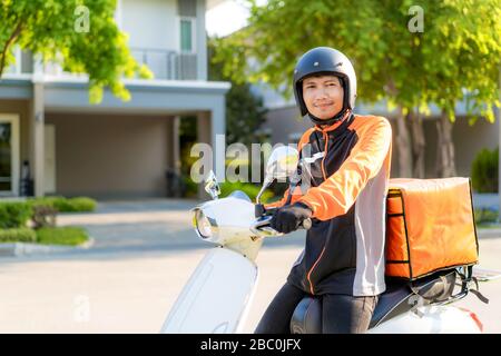 Un homme asiatique courier sur le scooter livrant de la nourriture dans les rues de la ville avec une livraison de nourriture chaude de prendre des escapades et des restaurants à la maison, livraison express de nourriture A Banque D'Images