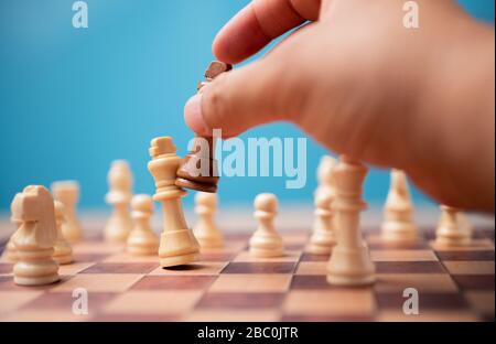 La main de l'homme d'affaires tenant le roi brun des échecs et le copain concurrent et gagner les jeux. Le concept de leadership doit avoir une stratégie commerciale et c Banque D'Images