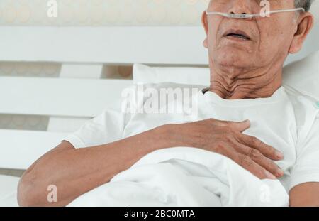 Triste homme senior allongé sur le lit de l'hôpital et avec un tube respiratoire nasal pour le traitement respiratoire. Concept de soins de santé pour les personnes âgées, quarantaine Banque D'Images