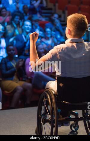 Enceinte féminine en fauteuil roulant gestuelle sur scène pour encourager le public Banque D'Images