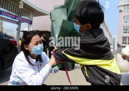 Cangzhou, la province chinoise de Hebei. 2 avril 2020. Le du Xiangxiang, une travailleuse médicale qui soutient la province de Hubei, atteinte de virus, reçoit un bouquet de fleurs de son fils de 6 ans Hao Yibo lors de son retour à la maison dans le comté de Yanshan dans la ville de Cangzhou, dans la province de Hebei en Chine du nord, le 2 avril 2020. Les membres du cinquième lot d'équipes d'assistance médicale de la province de Heibei sont retournés chez eux après 14 jours de quarantaine. Crédit: Fu Xinchun/Xinhua/Alay Live News Banque D'Images