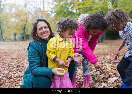 Portrait bonne mère et enfants jouant en automne feuilles Banque D'Images